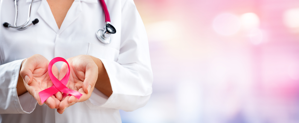 Physician holding pink ribbon for breast cancer awareness